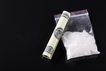 Rolled hundred dollars banknote and bag with cocaine