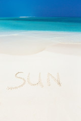 Fototapeta na wymiar Handwritting inscription word SUN on sandy beach