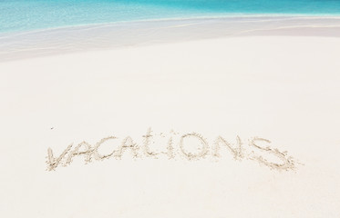 Handwritting inscription word VACATION on sandy beach