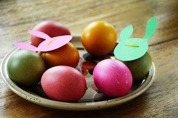 Festive dinner table set for easter brunch decorated in green and pink colours. Close up details of easter eggs with paper cut-out mask.