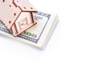 Wooden model of house on stack of dollar banknotes over white background