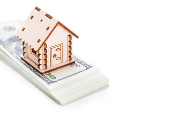 Wooden model of house on stack of dollar banknotes over white background