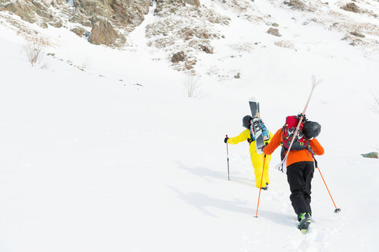 two ski freerider climbs the slope into deep snow powder with the equipment on the back fixed on the backpack.