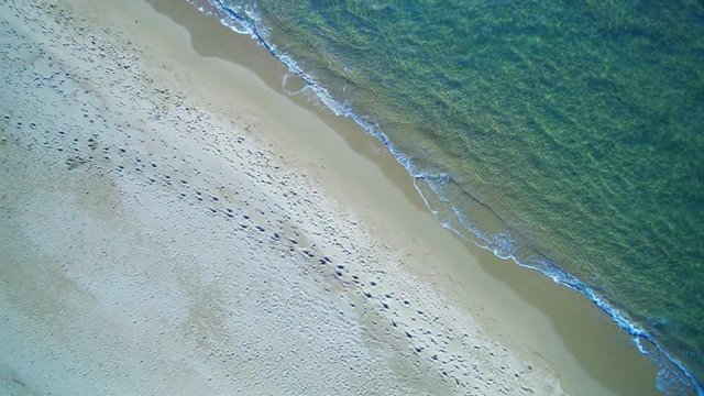 Aerial view waves break on white sand beach