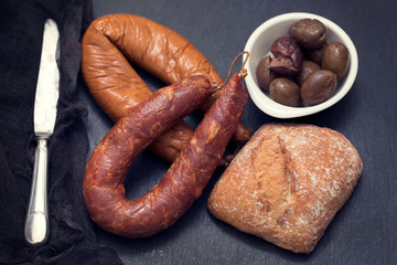 smoked sausages with bread on black ceramic board