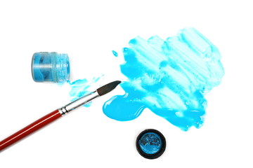 Spilled blue watercolor with bottle and paintbrush isolated on white background, top view