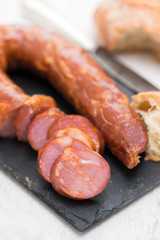 smoked sausages with bread on black ceramic board