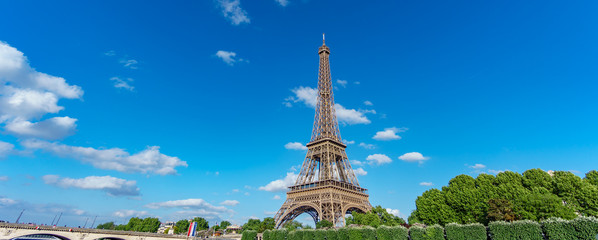The Eiffel Tower panorama over trees, blue sky