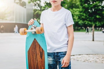 Summer day. Young millennial boy dressed in white t-shirt is stands outdoor. Mock up. Space for...