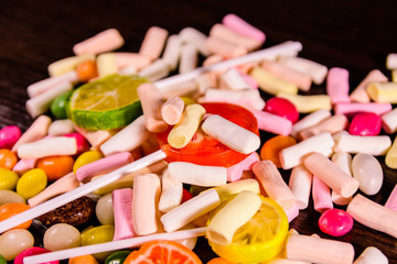 Different multi colored candies on a dark wooden table