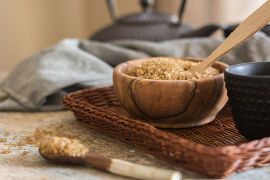 Wooden Bowl full of sugar cane brown, accompanied by a teapot.
