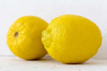 Two yellow lemon fruit on a white background.