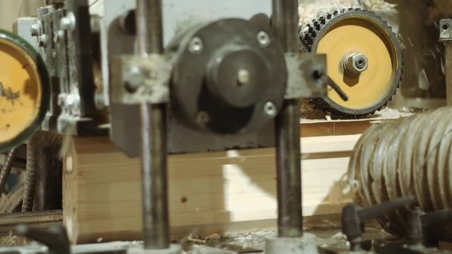 Spinning spiked wheels of bar refiner machine working on wood at sawmill production, close up