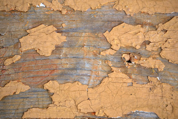 Texture of a peeling yellow paint on an old wooden surface.
