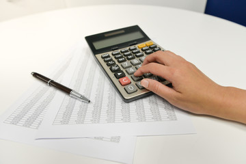 Woman hand is using the calculater to calculate the finance document