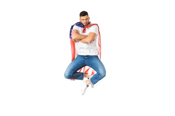 handsome young man with american flag jumping with crossed arms and looking at camera isolated on white
