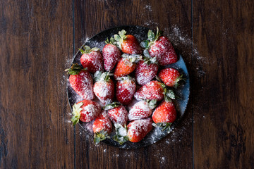 Fresh Organic Ripe Strawberries with Powdered Sugar on Black Plate.