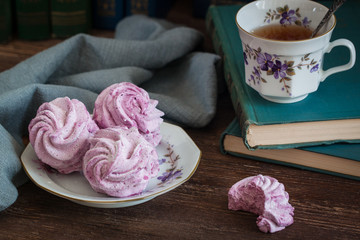 Homemade marshmallow or zephyr with a cup of tea over the wooden background.