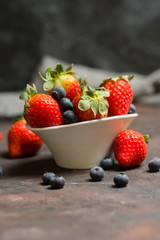 Full of ceramic bowl with blueberries and strawberries  on the stone table.