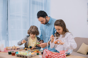 young father and children painting eggs for easter holiday
