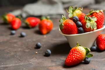 Full of ceramic bowl with blueberries and strawberries  on the stone table.
