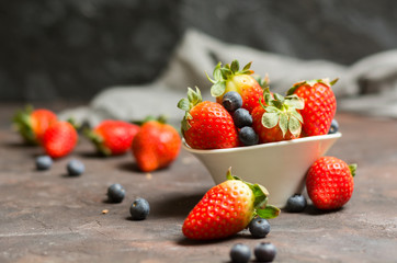 Full of ceramic bowl with blueberries and strawberries  on the stone table.