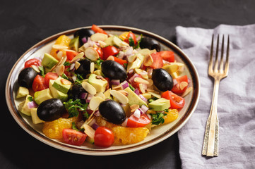 Salad with oranges, olives, tomatoes, avocado and almond.