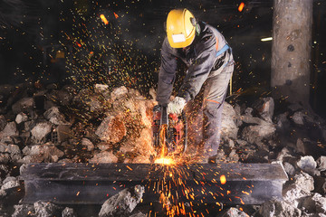 Construction worker cutting an iron beam. - obrazy, fototapety, plakaty
