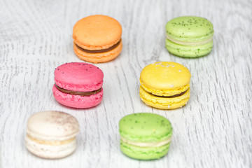 Six multicolored macarons on a light wooden table
