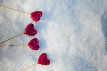 Four red hearts laying on white snow. Top view, space for text