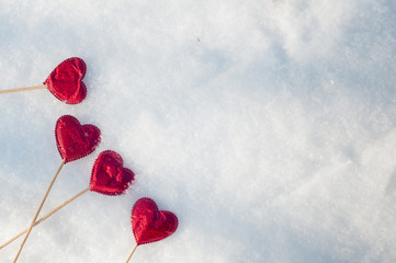 Nice love concept. Flat lay of red hearts on wooden sticks laying on white winter snow at the edge of frame