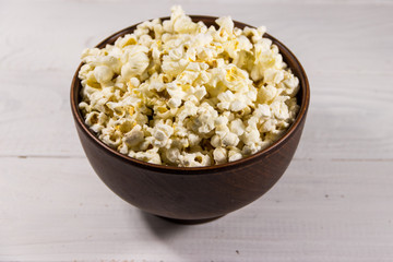 Bowl with popcorn on wooden table
