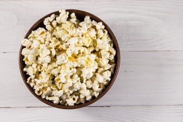 Bowl with popcorn on wooden table