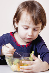 Beautiful child girl eating fruit salad (health, nutritious food concept)