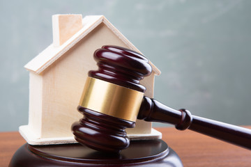 Real estate sale auction concept - gavel and house model on the wooden table