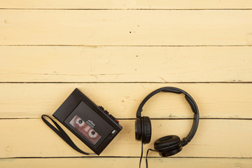 Retro cassette player with headphones on yellow background, flat top view