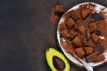 Chocolate truffle with avocado and cocoa powder on a brown background.