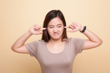 Fototapeta premium Young Asian woman block both ears with fingers.