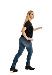 full length portrait of blonde girl wearing simple black shirt and jeans, standing pose wit back to...