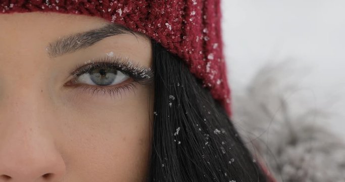 Close-up of woman open her eyes with snow on big eyelashes
