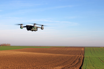 Fototapeta na wymiar The drone quad copter is flying over the plowed field