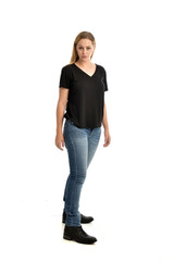Fototapeta premium full length portrait of blonde girl wearing black shirt and jeans, standing pose isolated on a white background.