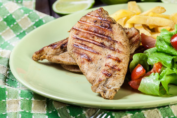 Grilled chicken breasts served with fries