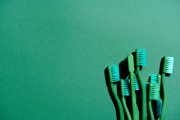 top view of green toothbrushes, on green with copy space