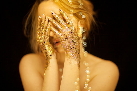 Beautiful woman in gold, golden hands, glitter sensual glamour studio shoot