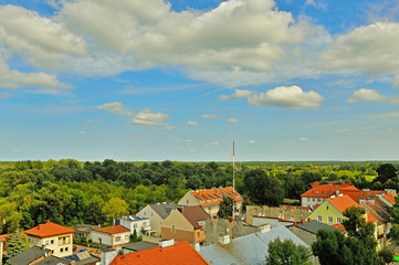 Błękitne niebo, białe chmury, zielone drzewa i czerwone dachy domów. © W Korczewski