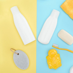 flat lay with bottles of lotion, toothbrush, pumice, soap and bath toy, isolated on blue and yellow