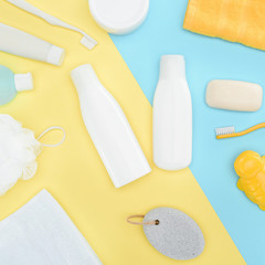 flat lay with body lotion in bottles, toothbrushes, pumice, towel and soap, isolated on blue and yellow
