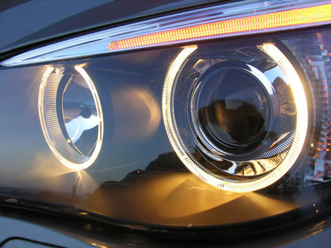 A View Of A Car's Left Headlight On. The Photo Of The Headlamp Could Be Appealing For An Automotive Lighting System Advertising Or Be An Attractive 