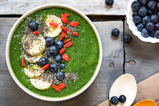 Green smoothie made of Spinach with Banana, Mango in a bowl with Blueberry ,Banana,Goji berry and  Chia seeds topping